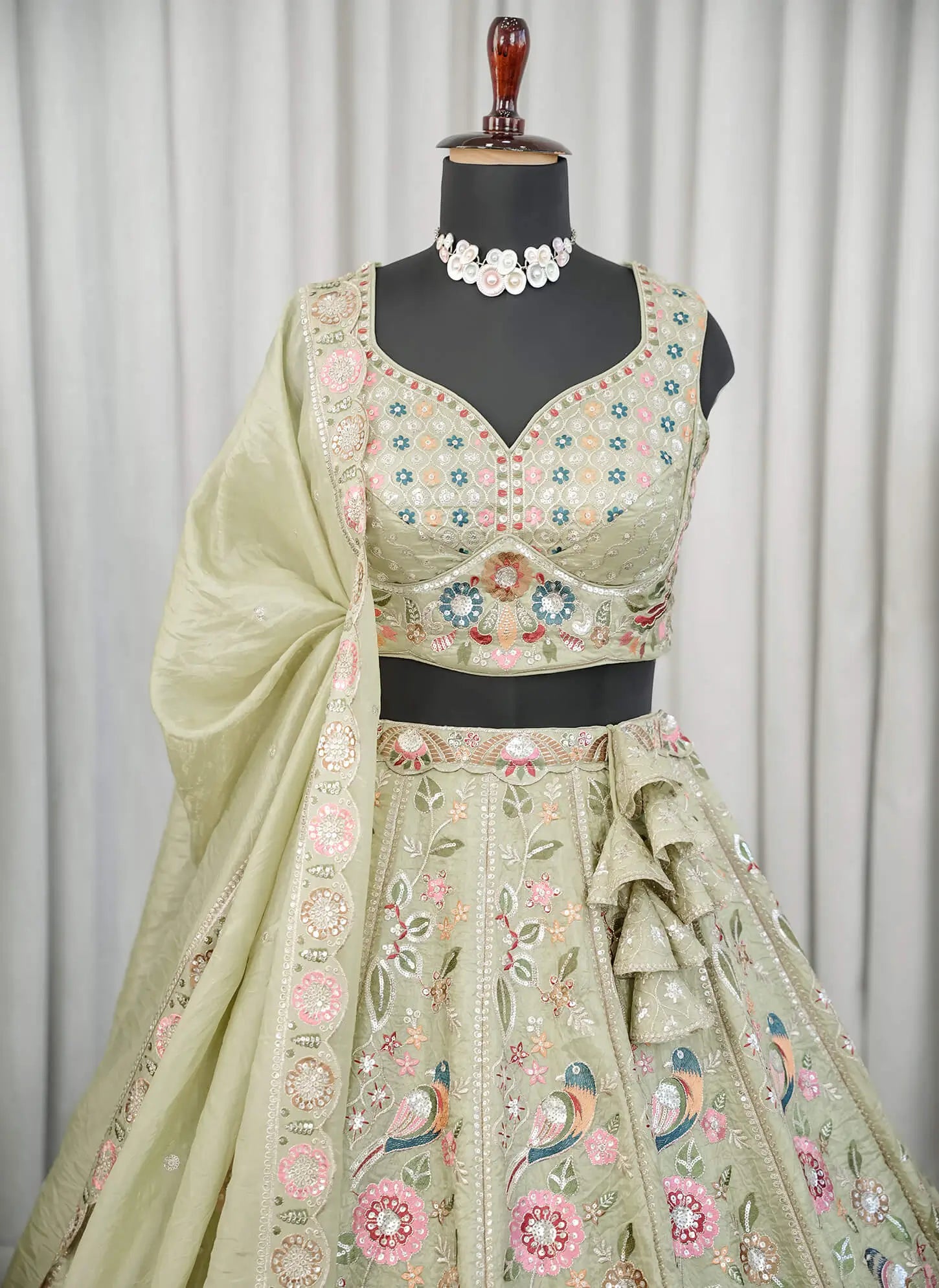 Close-up detail of pastel green floral embroidery on lehenga choli fabric