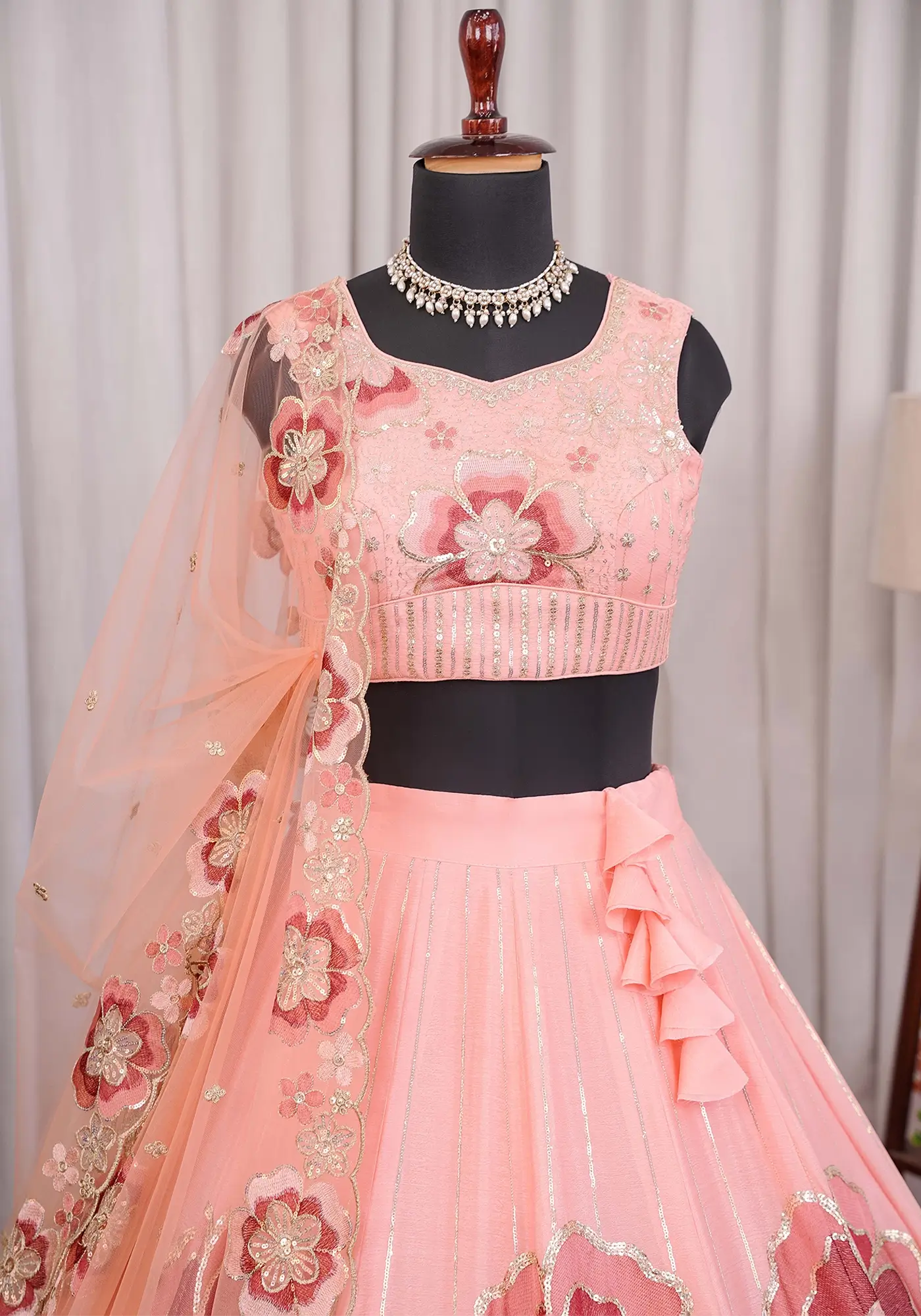 Close-up of peach lehenga choli blouse with floral embroidery and sequin work festive ethnic outfit